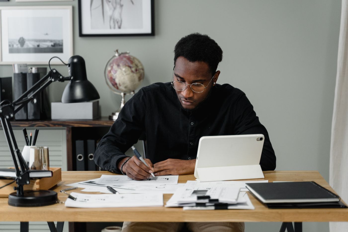 A man working through paperwork and a tablet at a desk